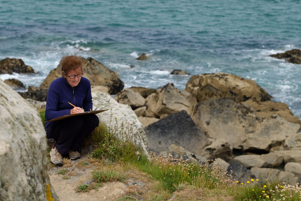 Women sitting and drawing by cliffs