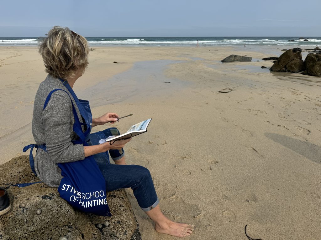 student from the st ives school of painting on the beach sketching in a Nina Squire Pastel painting workshop