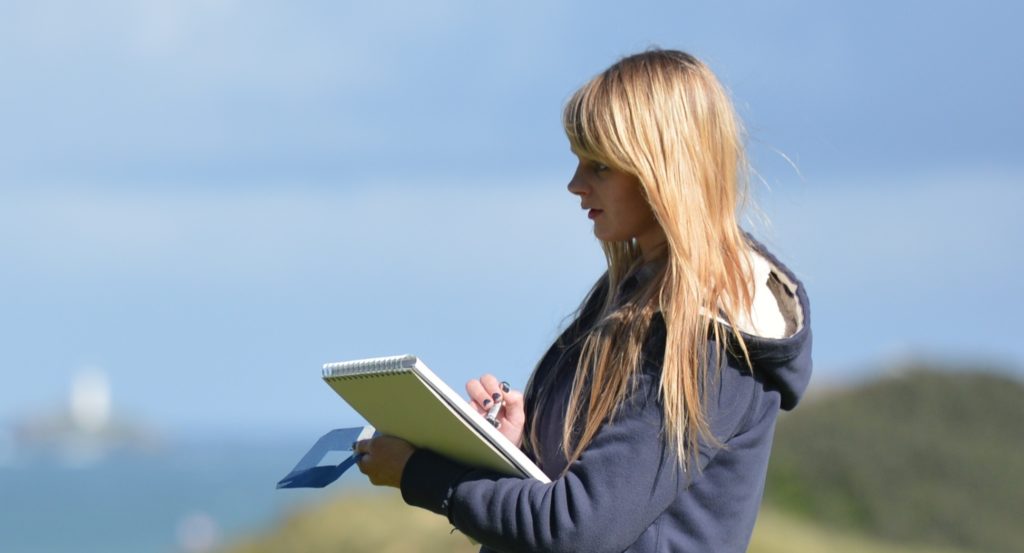 Girl drawing with view of lighthouse and sea