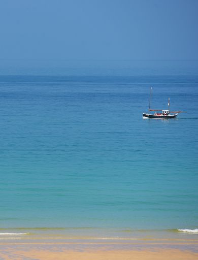 Calm blue sea with cornish fishing boat.